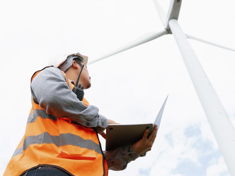 Engineer working on a wind farm atop a hill or mountain in the rural. Progressive ideal for the future production of renewable, sustainable energy. Energy generation from wind turbine.